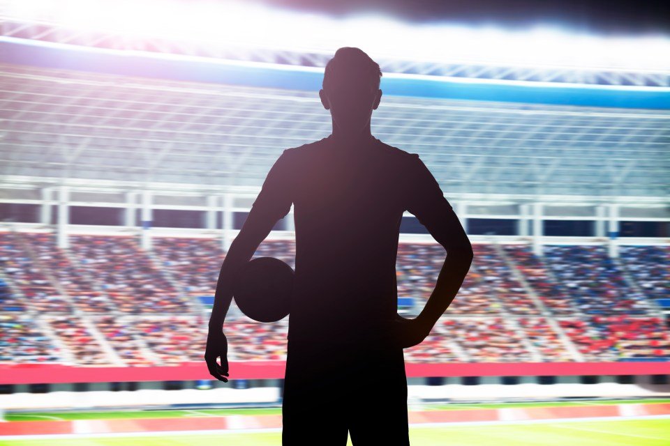 Silhouette of a man holding a football in a stadium filled with spectators.