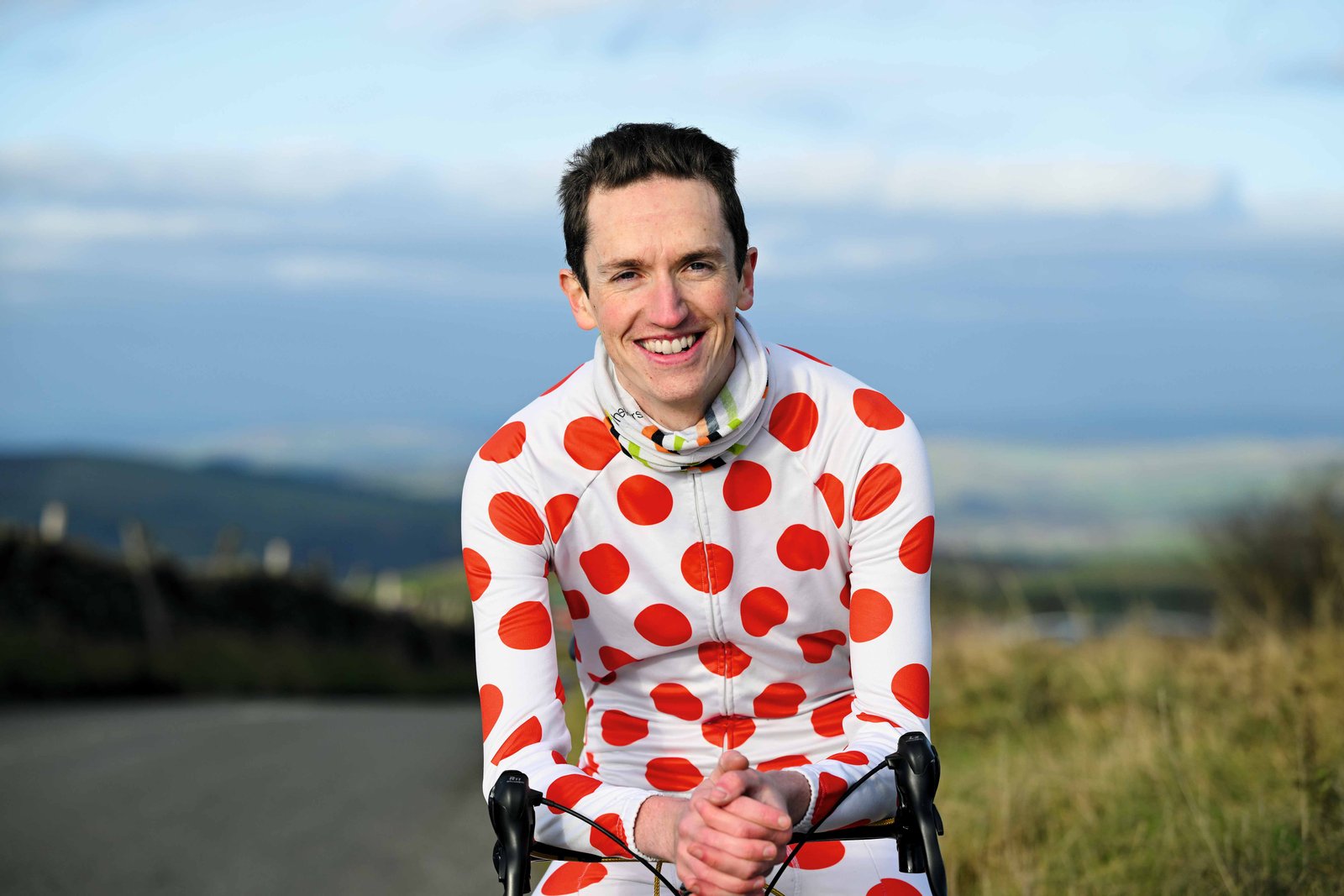 Man sits on bike, smiles into camera