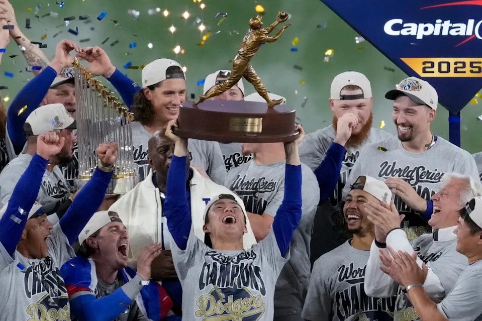 LA Dodgers World Series MVP Yoshinobu Yamamoto holds his trophy as teammates celebrate their win. AP