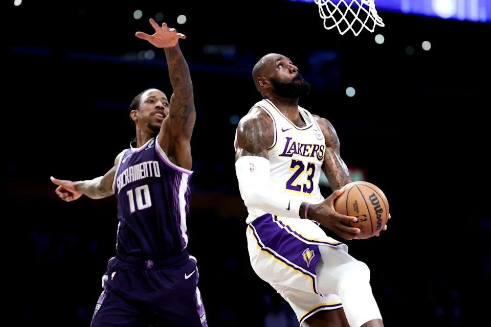 Lakers forward LeBron James, right, glides past Kings forward DeMar DeRozan for a reverse dunk during a game in December.