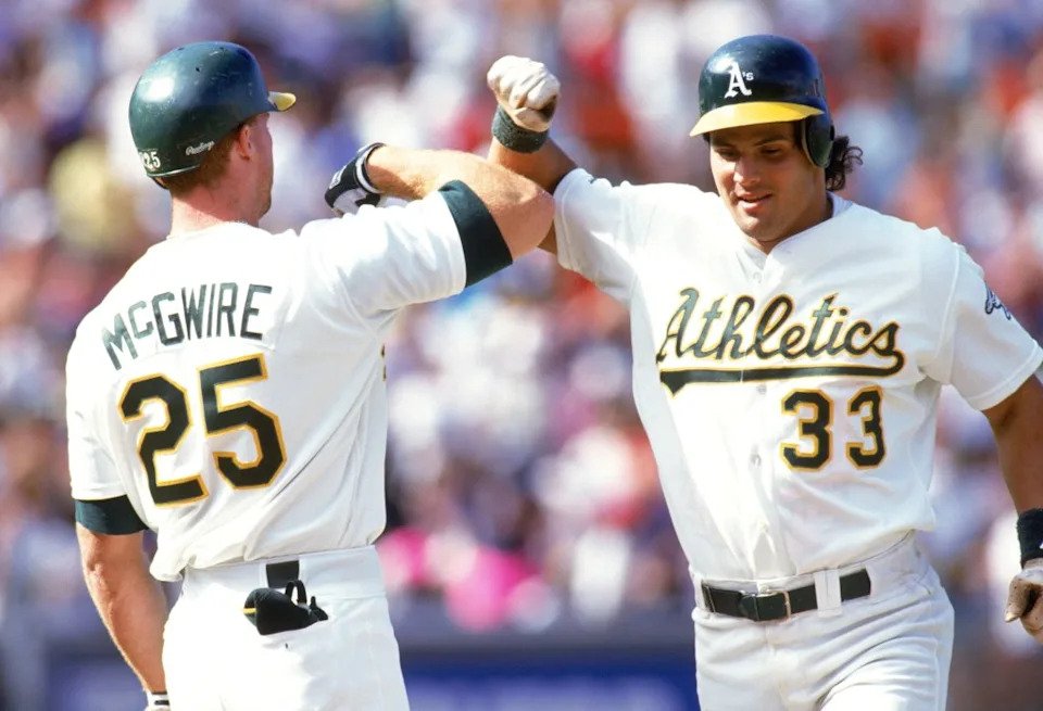 Jose Canseco and Mark McGwire of the Oakland Athletics celebrate during a 1990 MLB season game at Oakland-Alameda County Coliseum in Oakland, California. Getty Images
