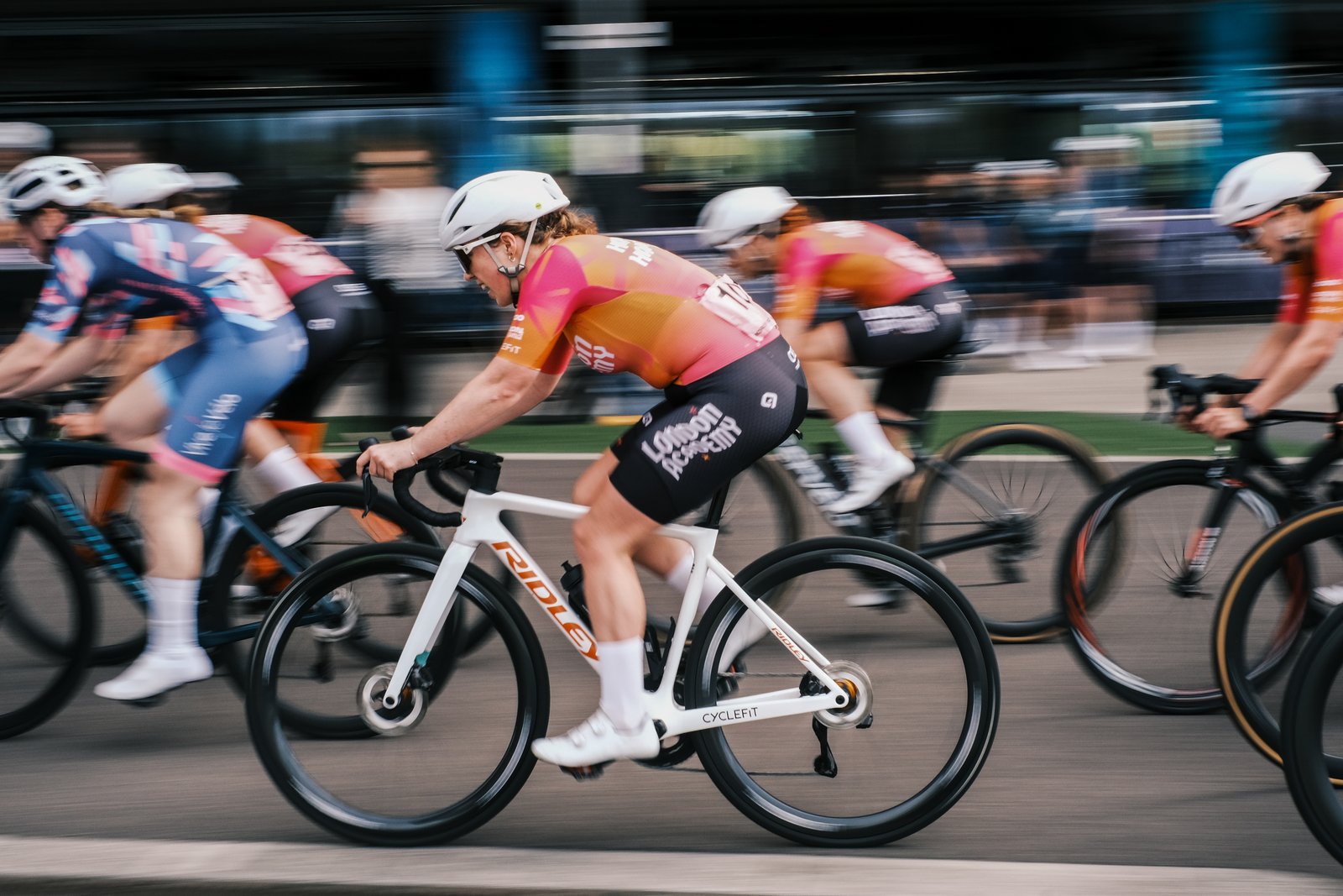 A woman races a bike in a pink jersey