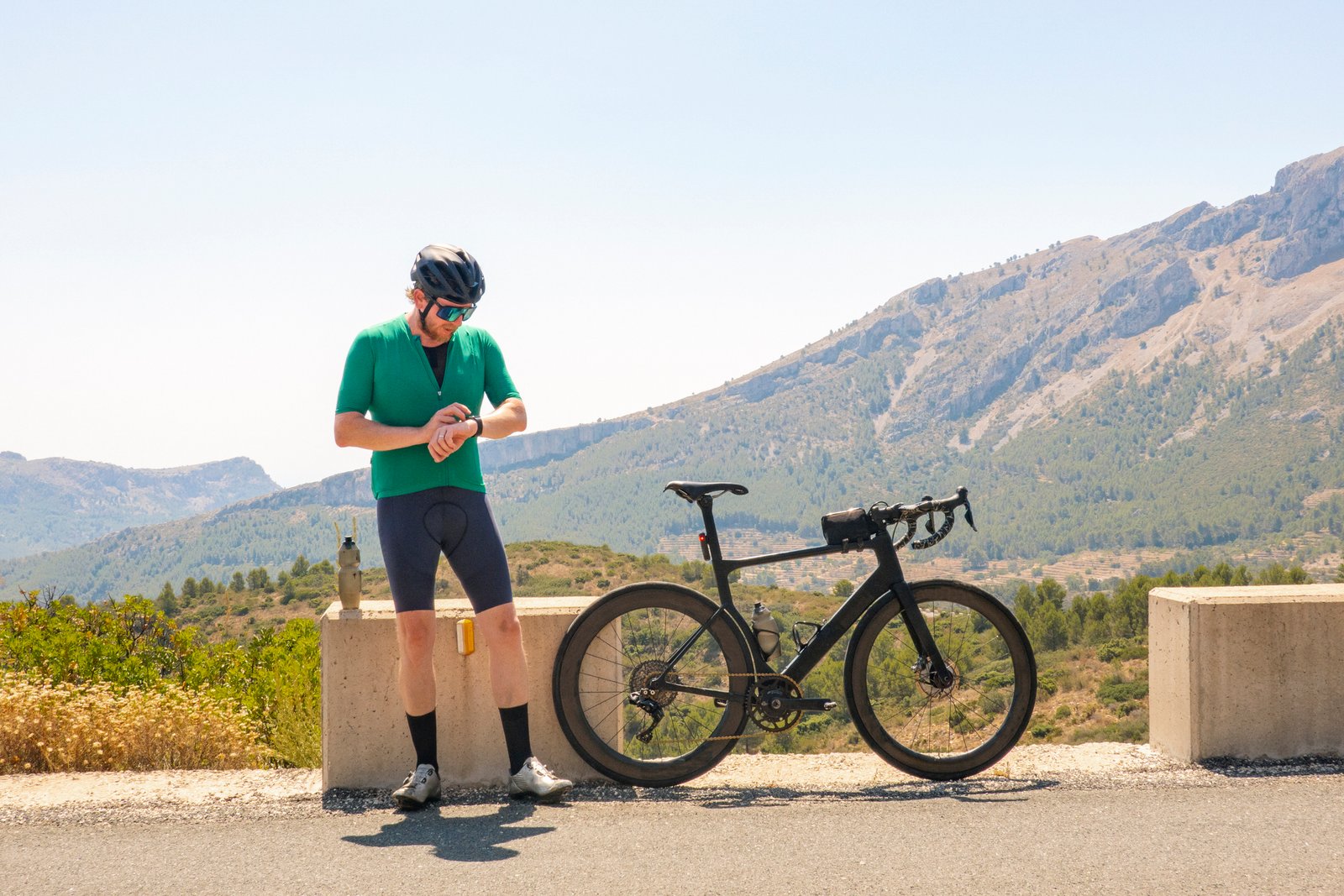male cyclist standing by his road bike as he checks his smart watch